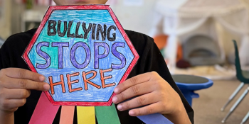Student holding a sign saying 'Bullying stops here"