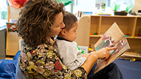 Head Start Teacher with Student in arms reading a book