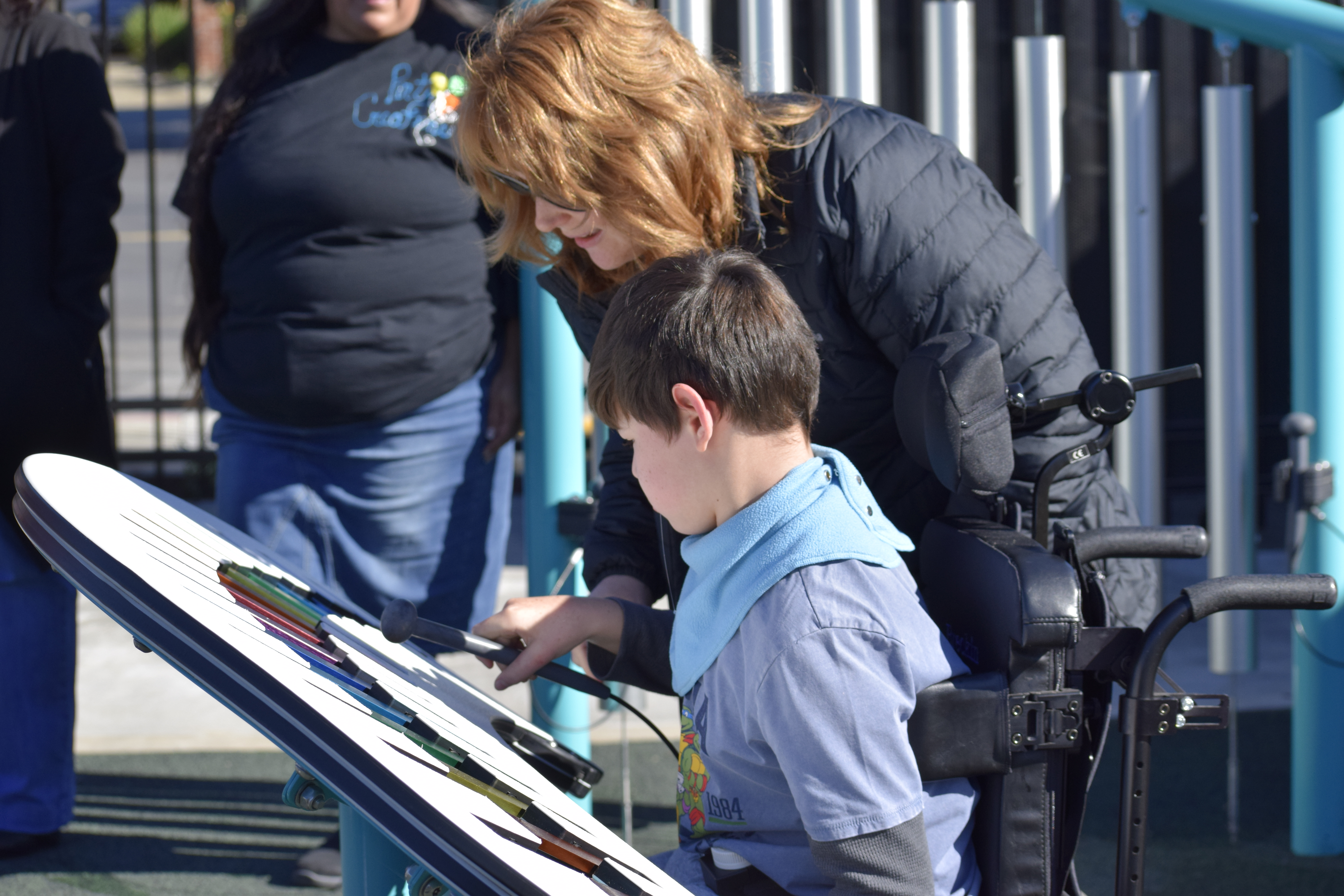 student in wheelchair playing with noise-making feature in playground 