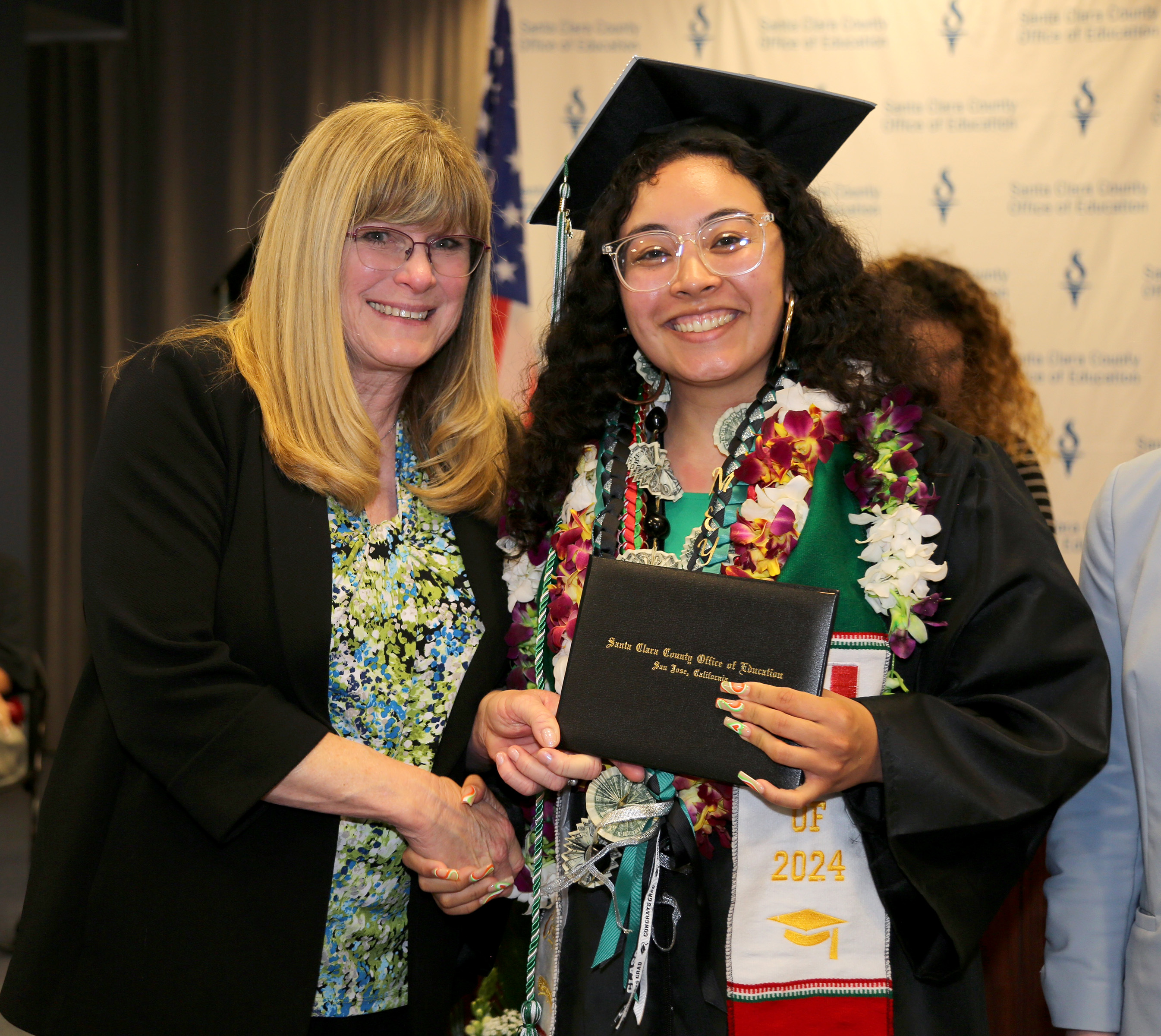 A school principal shaking the hand of high school graduate