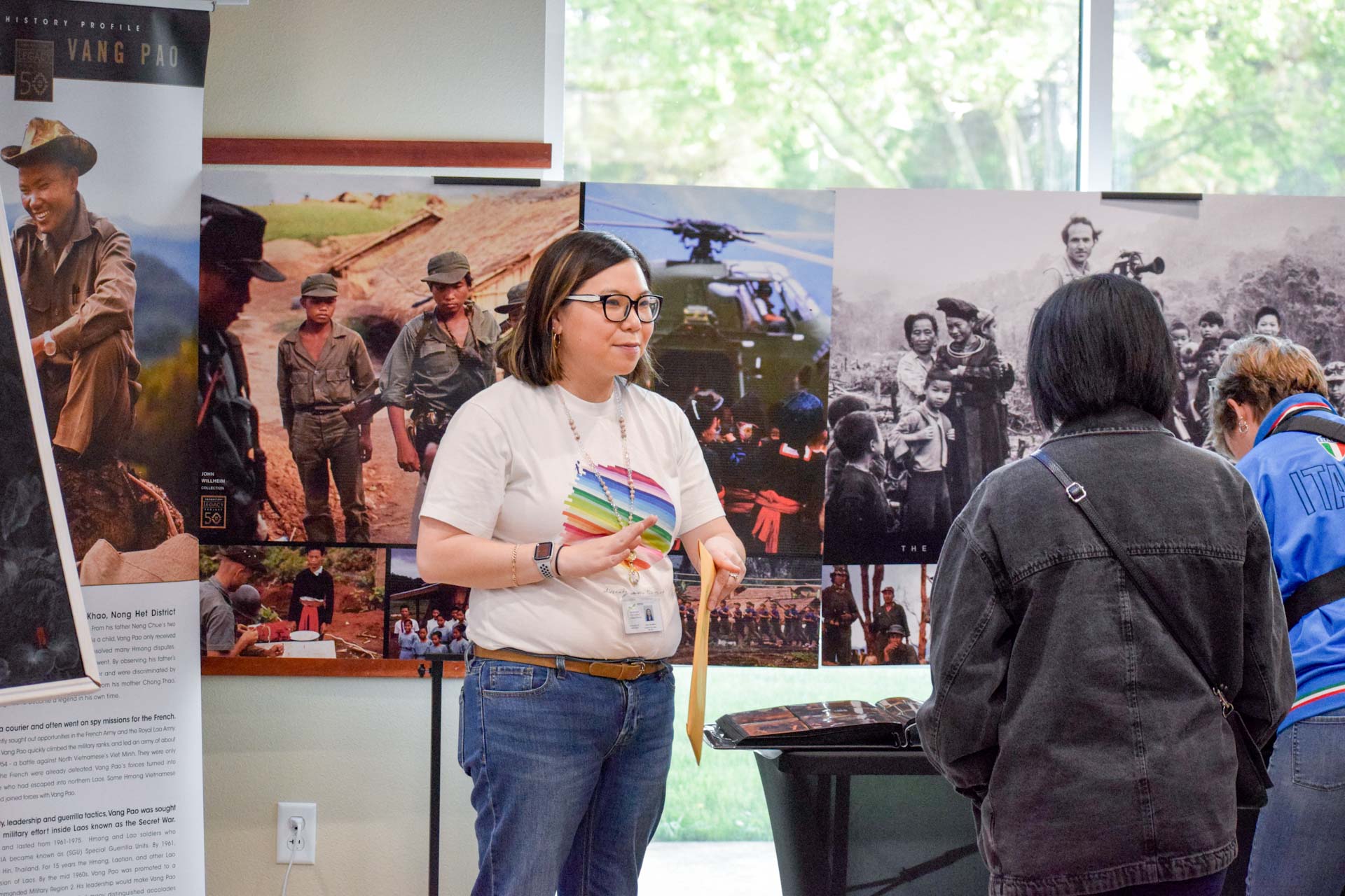 Conference presenter engaging with attendees with posters of Hmong history photos