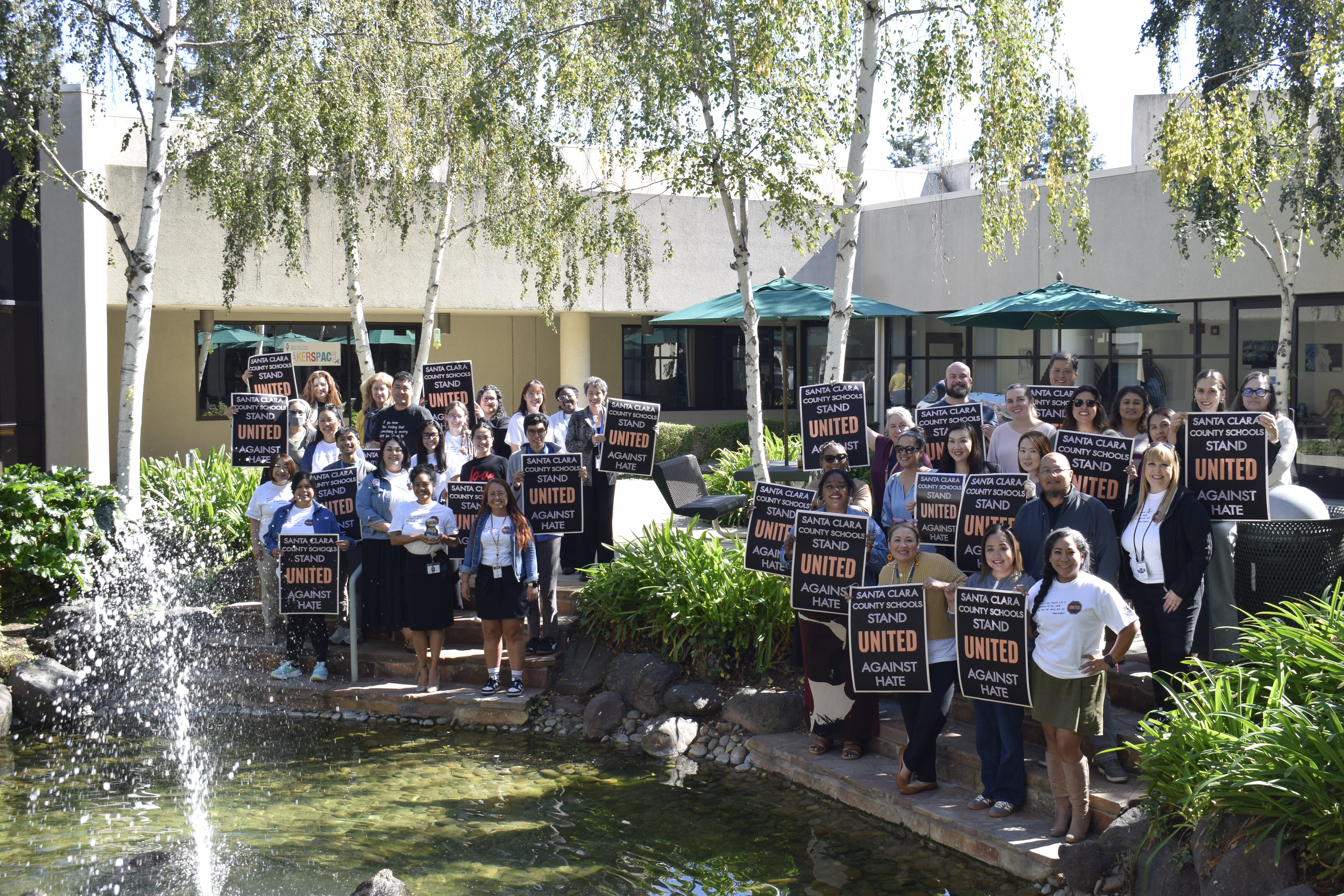 SCCOE Staff members displaying United Against Hate Posters outside in the courtyard