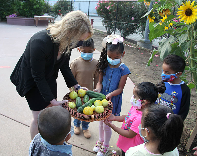 Dr. Dewan in mask sharing crops with kids